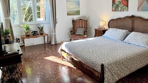 A bedroom with a large bed, a wooden nightstand, a chair, a desk with a telephone, and a window with curtains. - Vacation House Oleandri Bracciano Lake Rome (Bracciano)