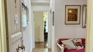 A hallway with a wooden door, a red sofa with patterned cushions, and a framed picture on the wall. - Vacation House Oleandri Bracciano Lake Rome (Bracciano)