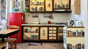 A kitchen with wooden cabinets, a red refrigerator, and various bottles and cans on shelves. - Vacation House Oleandri Bracciano Lake Rome (Bracciano)