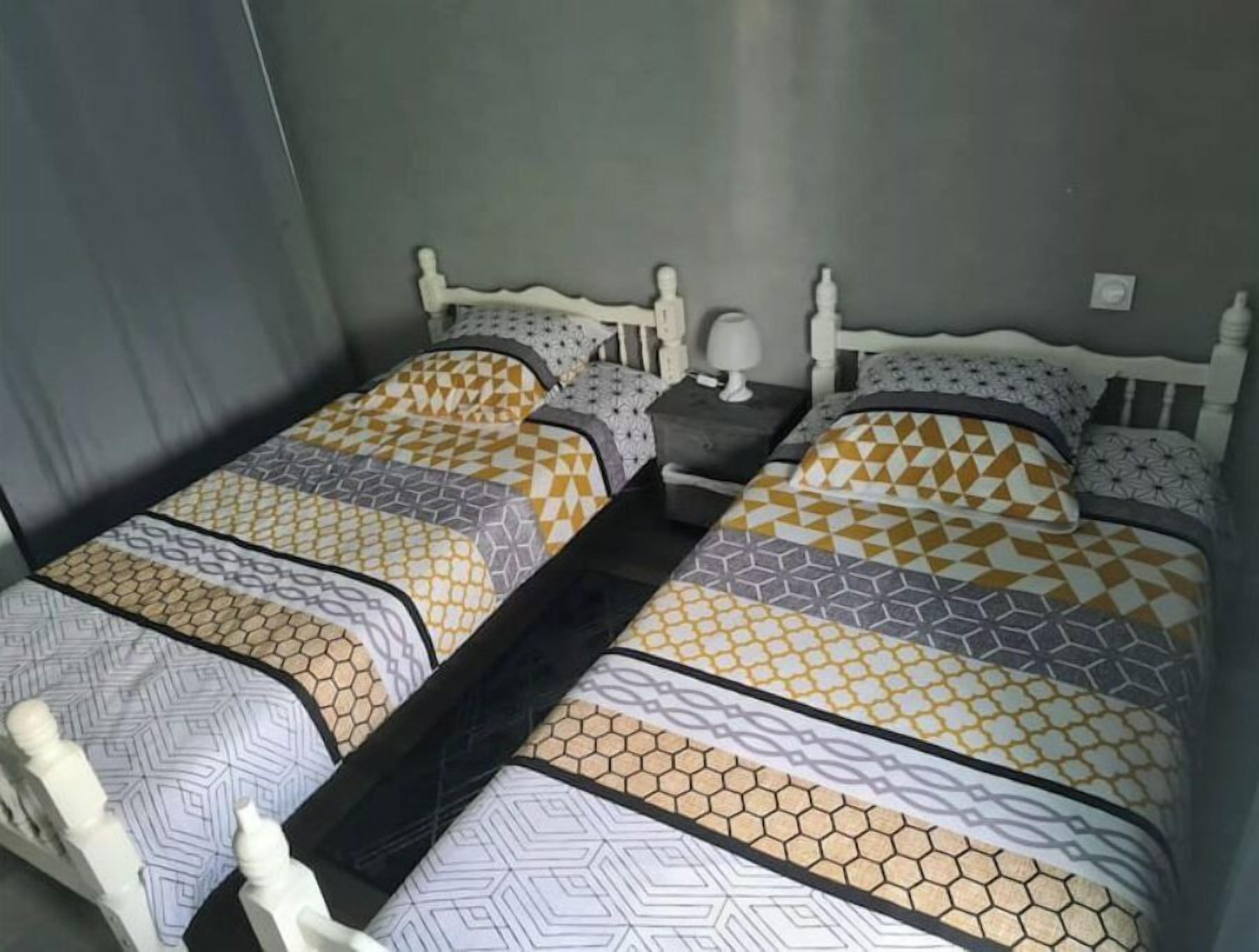 A double bed with patterned bedding in a room with a grey wall and a white headboard.