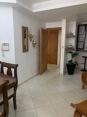 Cozy living area with a dining table and chairs, a door leading to another room, and a potted plant.