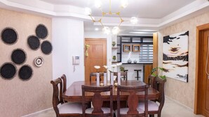 Un coin repas comprenant une table ronde en bois, six chaises, un lustre et un mur orné de motifs circulaires.