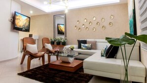Un salon moderne avec un canapé, des fauteuils, une table basse et un téléviseur.