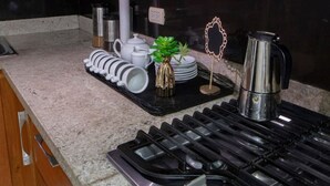 Une cuisine moderne équipée d’une cuisinière à gaz, d’appareils électroménagers en acier inoxydable et de meubles de rangement en bois.