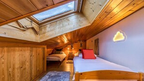 Un dormitorio acogedor en el ático con tragaluz, paredes de madera, una cama con almohadas y una alfombra mullida.