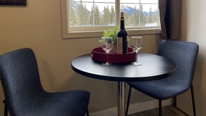Une petite table ronde, deux chaises, une bouteille de vin et deux verres à vin.