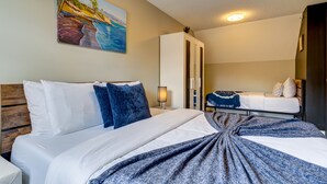 Une chambre d’hôtel avec un lit, une table de chevet, une lampe, une armoire et un tableau au mur.