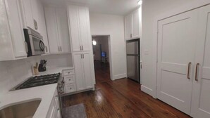Eine moderne Küche mit weißen Schränken, einem Edelstahl-Kühlschrank und einem Holzboden.