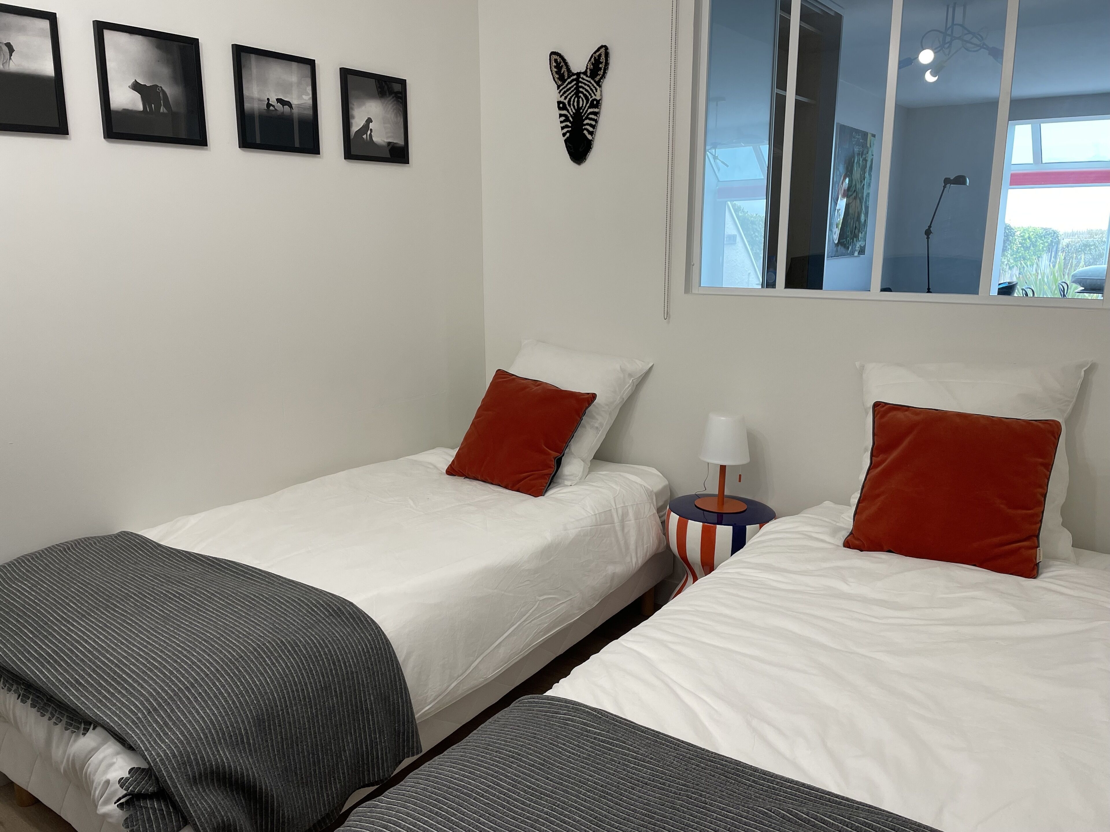 Habitación de hotel con dos camas, una ventana y un adorno de cabeza de cebra montado en la pared.