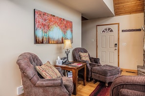 A living room with two armchairs, a small table, and a painting on the wall.