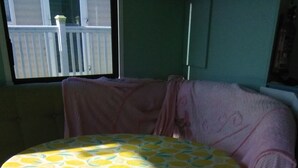 A round table with a lemon pattern tablecloth, positioned on a wooden floor with a view of a balcony in the background. - Charming 3-bed Caravan in Camber Food Rest (Rye)