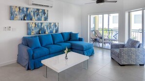Ein modernes Wohnzimmer mit einem blauen Sofa, einem weißen Couchtisch und einem gemusterten Sessel.