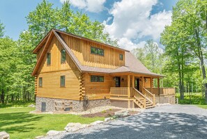 A log cabin with a porch and a stone foundation.