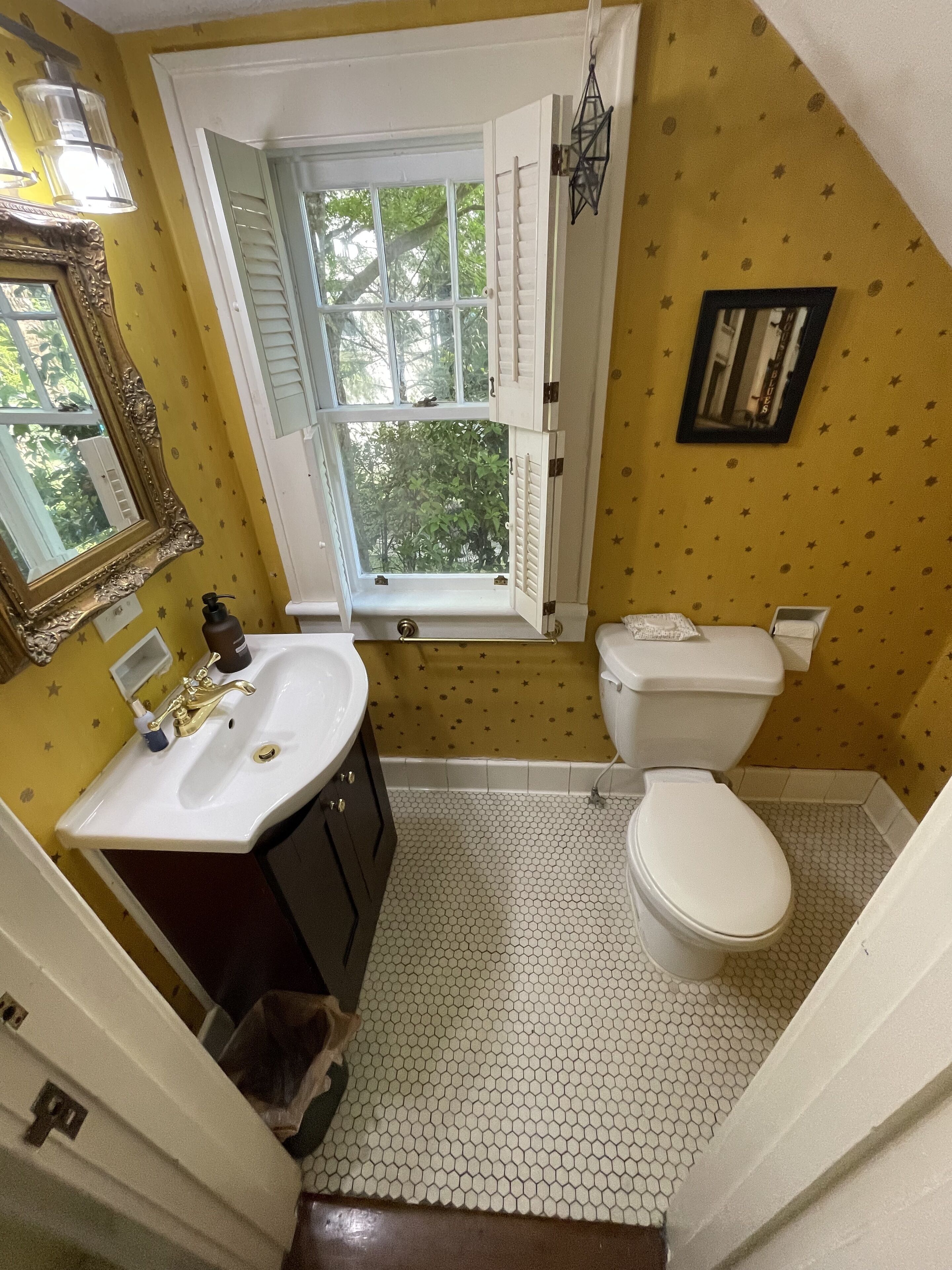 A bathroom with a sink, toilet, and window.