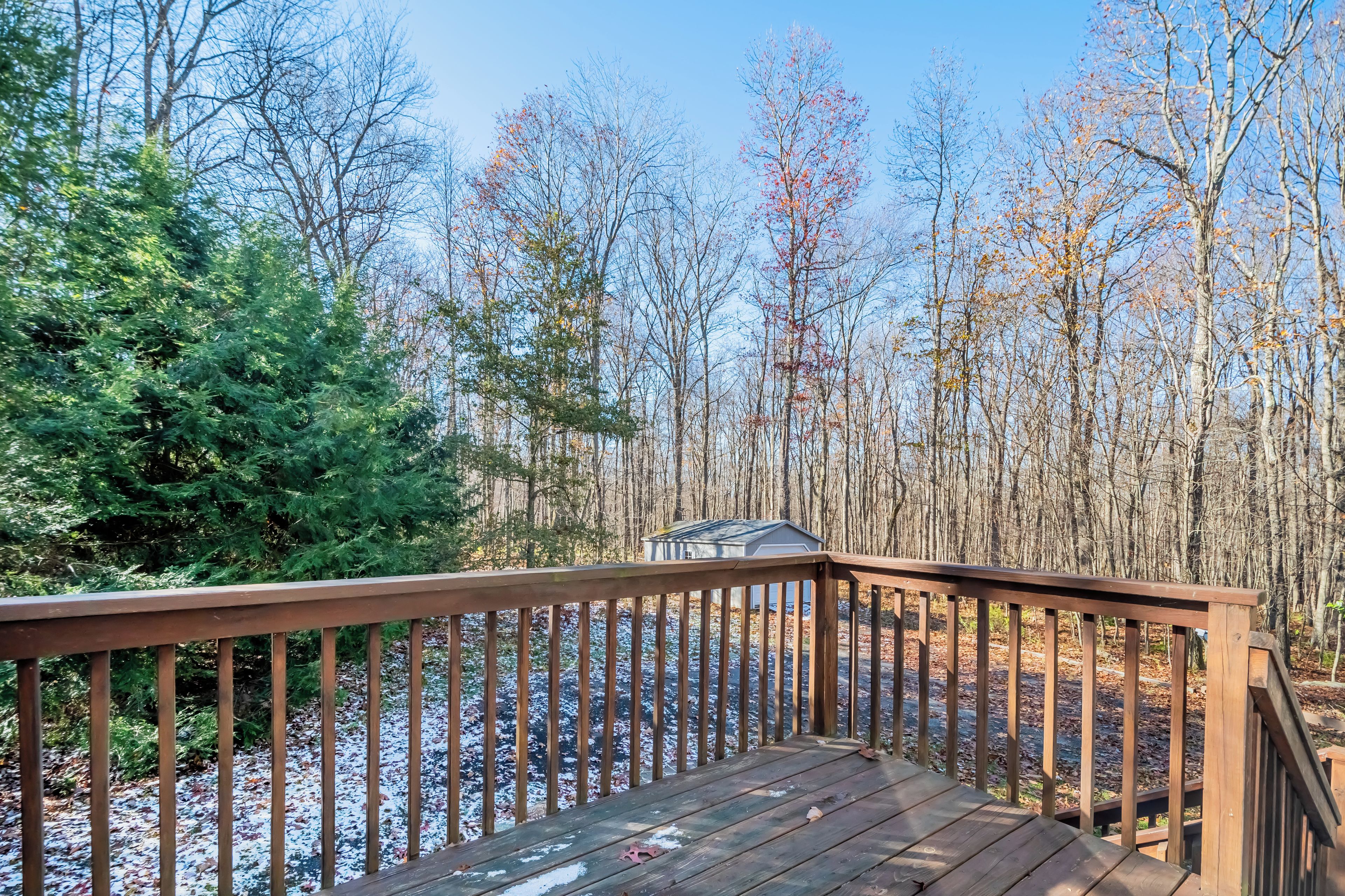 A wooden deck with a view of a forested area and a small shed.