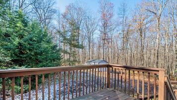 A wooden deck with a view of a forested area and a small shed.