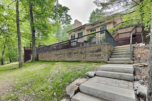 A residential property with a stone staircase leading to a house, surrounded by trees and a grassy area.