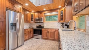 A modern kitchen with wooden cabinets, stainless steel appliances, and a granite countertop.