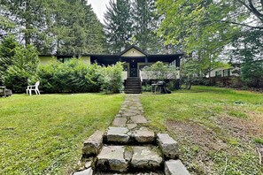Una casa con un sendero de piedra que conduce a la puerta principal, rodeada por un jardín cubierto de césped y árboles.