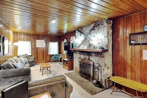 Una sala de estar acogedora con paredes de madera, chimenea, sofá, mesa de centro y televisor.