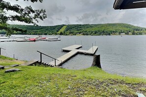 Un muelle a orillas del lago con una escalera que lleva a un embarcadero, rodeado de follaje y colinas.