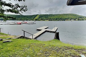 Un muelle a orillas del lago con una escalera que lleva a una zona cubierta de césped, rodeado de colinas y barcos.