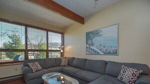 A living room with a gray sectional sofa, a glass coffee table, and a red patterned rug. - Ski Harbor 07 by Taylor Made Deep Creek (McHenry)