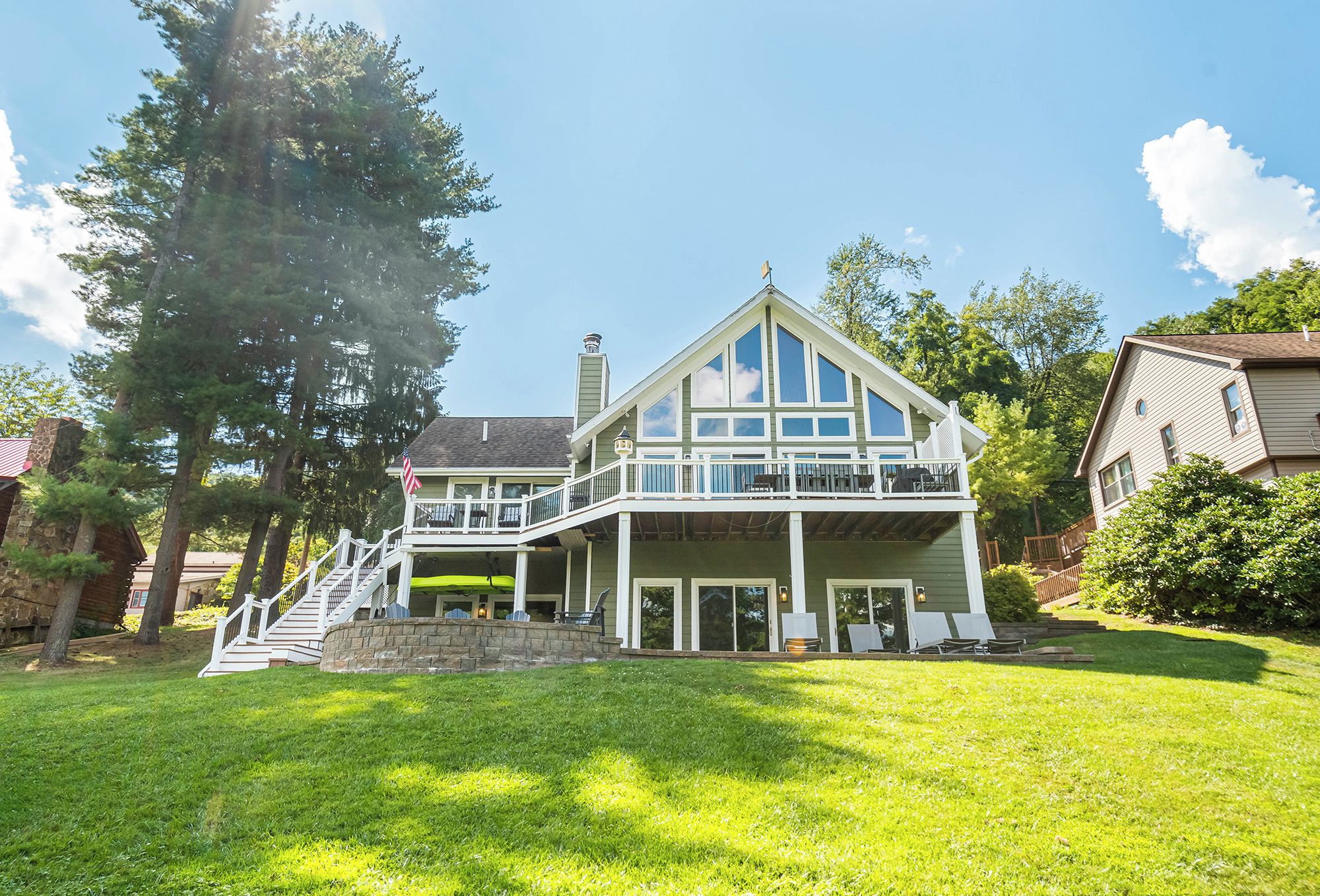 A two-story house with a balcony, a stone staircase, and a well-maintained lawn.