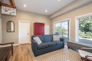 A cozy living room with a dark gray sofa, patterned cushions, a wooden bench, and a red cabinet.
