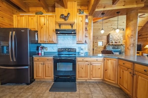 A wooden cabin kitchen with a refrigerator, stove, and wooden cabinets.
