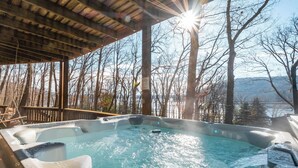 A hot tub area with a wooden deck and a view of trees and mountains. - Slip Away Chalet by Taylor Made Deep Creek (McHenry)