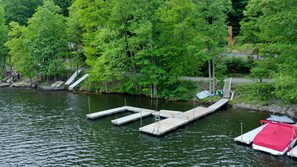 A dock extending into a calm body of water, surrounded by lush green trees and a small wooden structure. - Sm'oars by Taylor Made Deep Creek (McHenry)