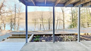 Ein überdachter Außenbereich mit Blick auf einen See und Bäume.