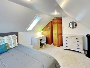 Um quarto com cama, escrivaninha, cômoda e guarda-roupa.