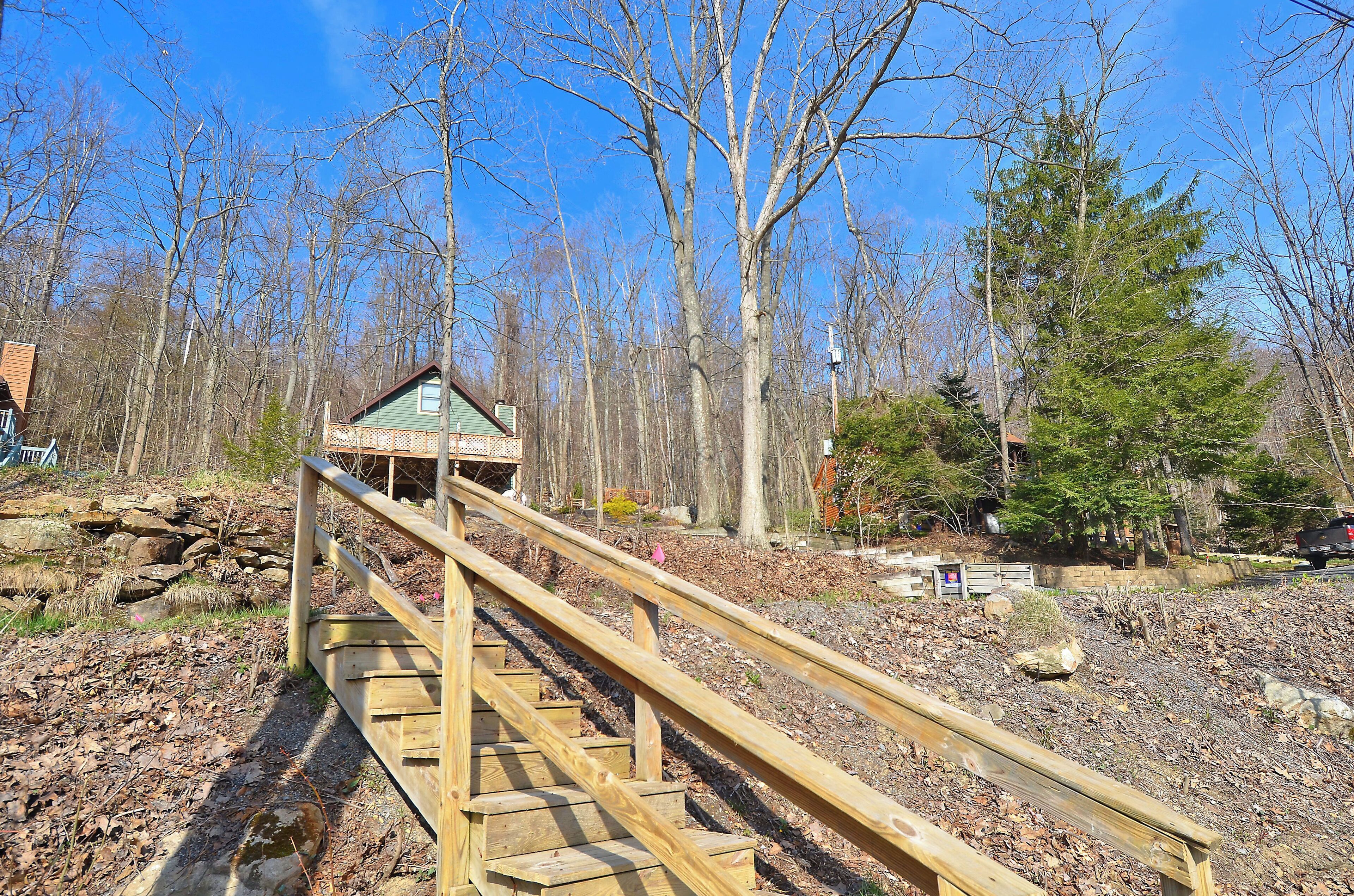 A wooden staircase leading to a gazebo in a wooded area.