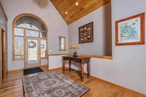 Experience the warmth of this inviting space, featuring a high ceiling, arched doorway, and traditional wooden table.