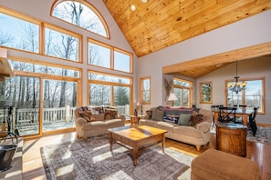 Relax in this spacious living area with a high ceiling, featuring a sofa set, coffee table, and dining table with chairs.