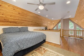 A bedroom with a large bed, wooden ceiling, and a view of the outdoors through a window. - Solitude by Taylor Made Deep Creek (Swanton)