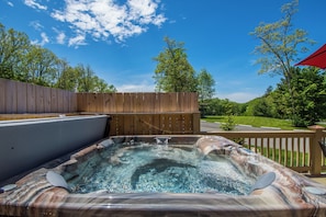 A hot tub with a wooden deck and a wooden fence in a backyard.
