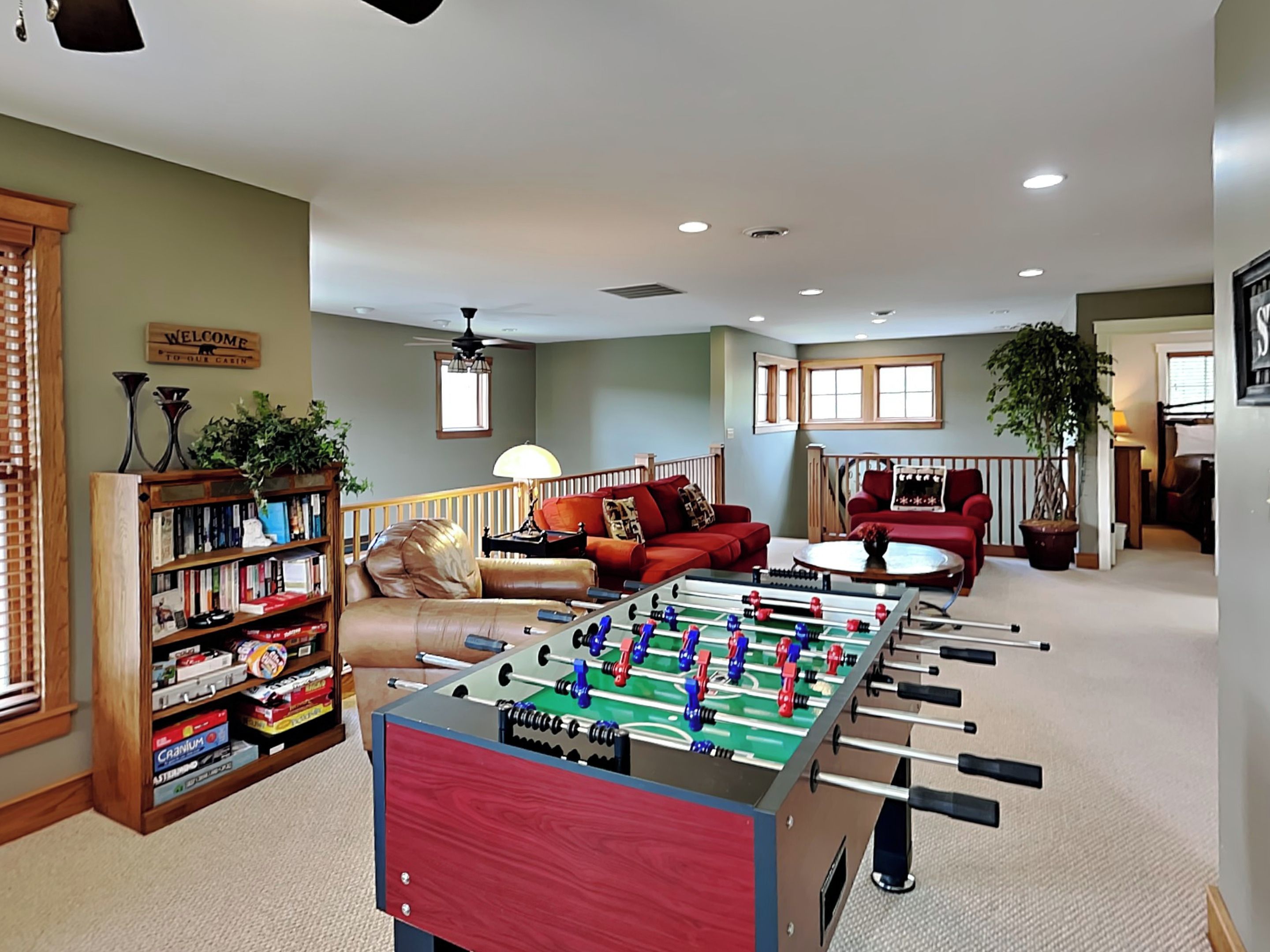 A cozy living room with a foosball table, a bookshelf, a red sofa, and a coffee table.