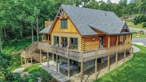 A log cabin with a deck, outdoor seating, and a hot tub. - Space Mountain by Taylor Made Deep Creek (McHenry)