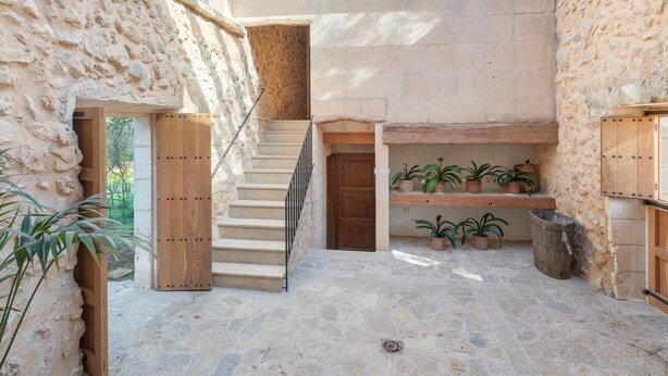 Un patio con paredes de piedra y una escalera de madera que sube a un nivel superior.