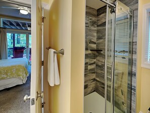 Ein Hotelzimmer mit Bett, einem Badezimmer mit Duschkabine und Blick ins Freie.