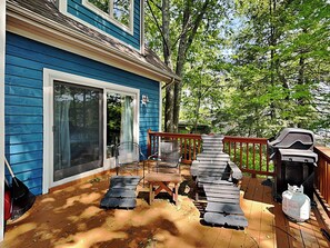 A blue house with a deck, a barbecue grill, and outdoor furniture.