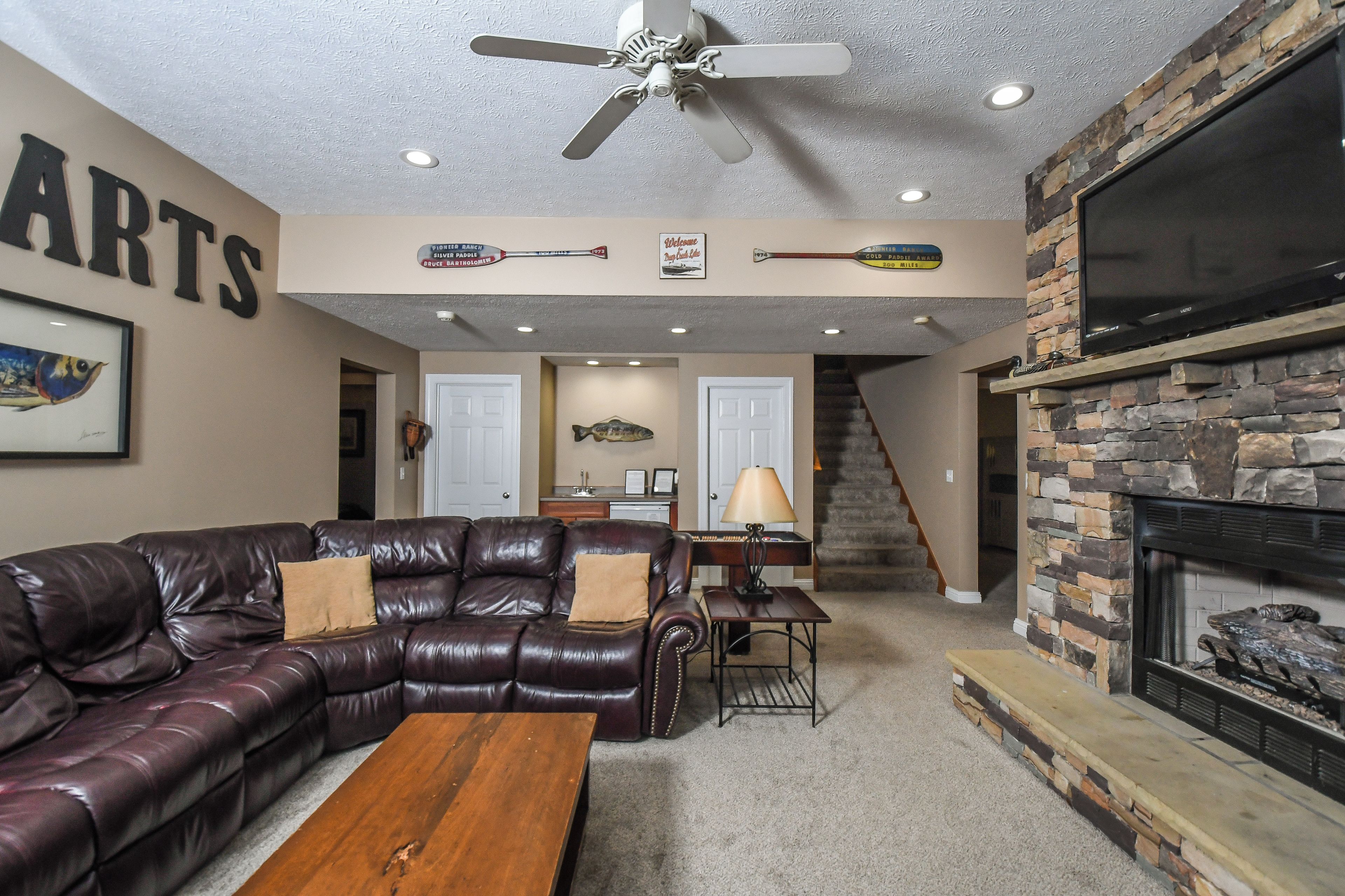 A living room with a leather couch, wooden coffee table, and a stone fireplace.
