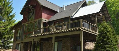 A two-story house with a stone facade, a balcony, and a covered porch.