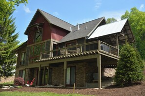 A two-story house with a stone facade, a balcony, and a covered porch.