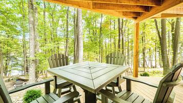 A wooden deck with a picnic table and chairs, surrounded by trees.