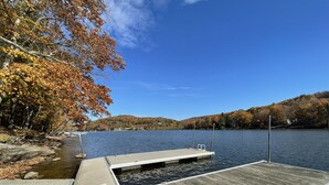 A wooden dock extending into a calm lake, surrounded by autumn-colored trees and hills in the background. - Stay Awhile by Taylor Made Deep Creek (McHenry)