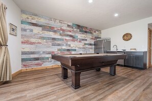 A pool table in a room with a wooden floor and a colorful, distressed wall. - Stay Awhile by Taylor Made Deep Creek (McHenry)